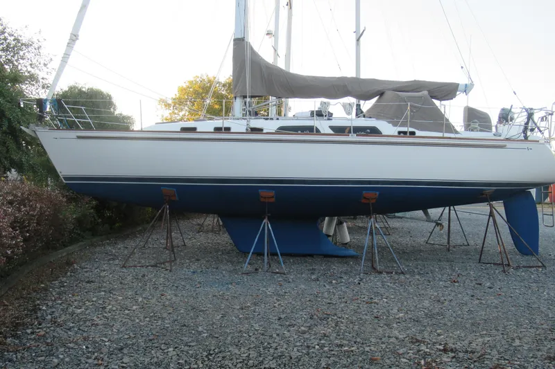 The Image of 2002 Sabre 402 sailboat on stands, displayed outdoors on gravel. - 1