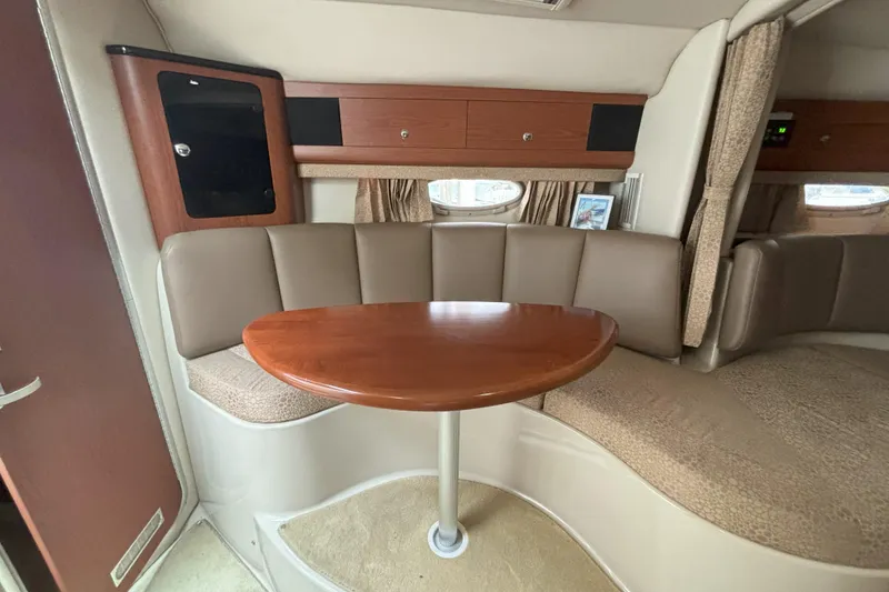 Slide: The Image of 2003 Chaparral 310 Signature cabin interior with curved seating and wooden table. - 18