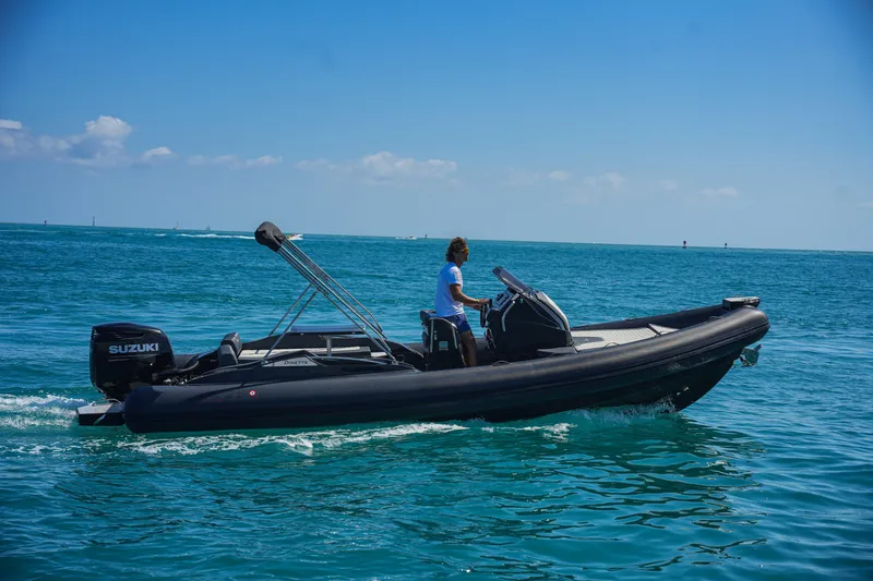 Slide: The Image of 2023 SPX RIB 25 Dinette boat cruising on clear blue water. - 2