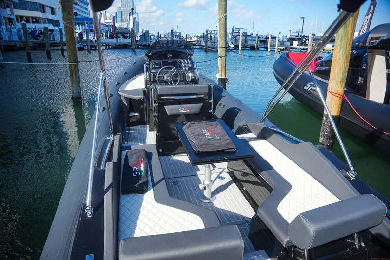 Slide: The Image of 2023 SPX RIB 25 Dinette boat docked at marina, featuring modern seating and table. - 7