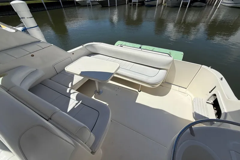 Slide: The Image of 1996 Sea Ray 330 Sundancer boat interior with white seating and table, docked by the water. - 11