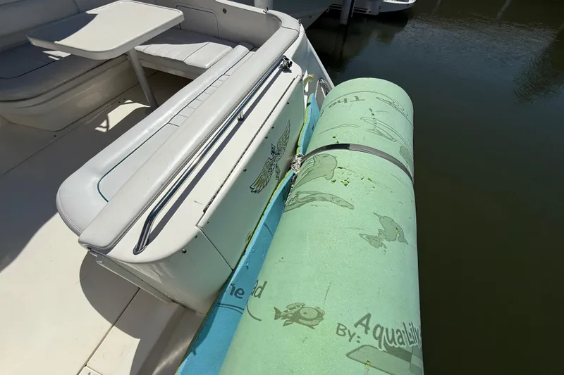 Slide: The Image of 1996 Sea Ray 330 Sundancer with aqua mat on deck, docked by water. - 17