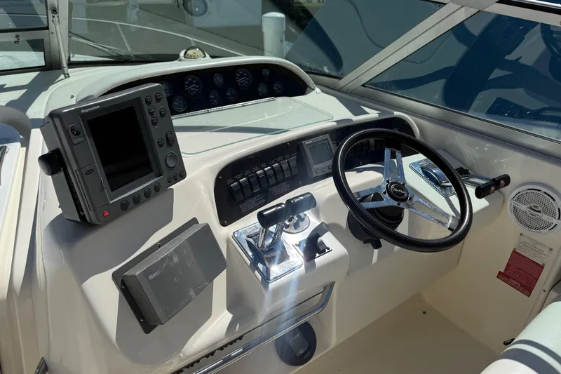 Slide: The Image of 1996 Sea Ray 330 Sundancer helm with steering wheel, navigation equipment, and control panel. - 19