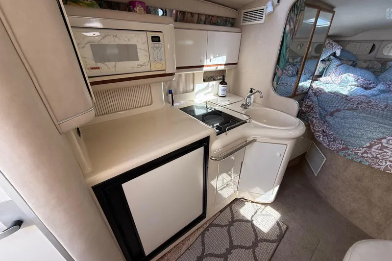Slide: The Image of 1996 Sea Ray 330 Sundancer interior with kitchenette and cozy sleeping area. - 25