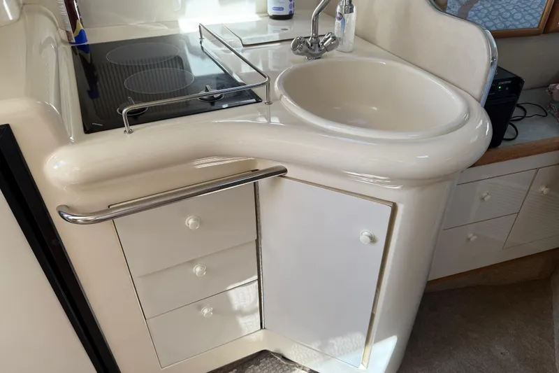 Slide: The Image of 1996 Sea Ray 330 Sundancer kitchen with sink, stove, and storage cabinets. - 28