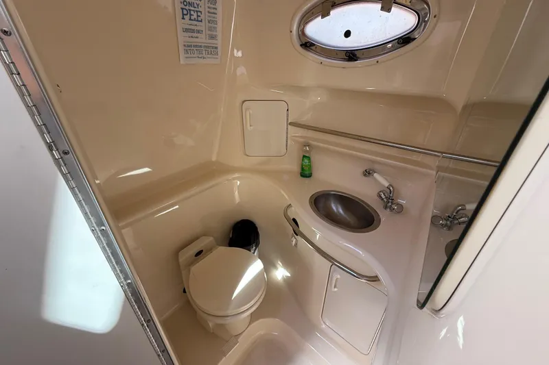 Slide: The Image of 1996 Sea Ray 330 Sundancer bathroom with toilet, sink, and porthole window. - 31