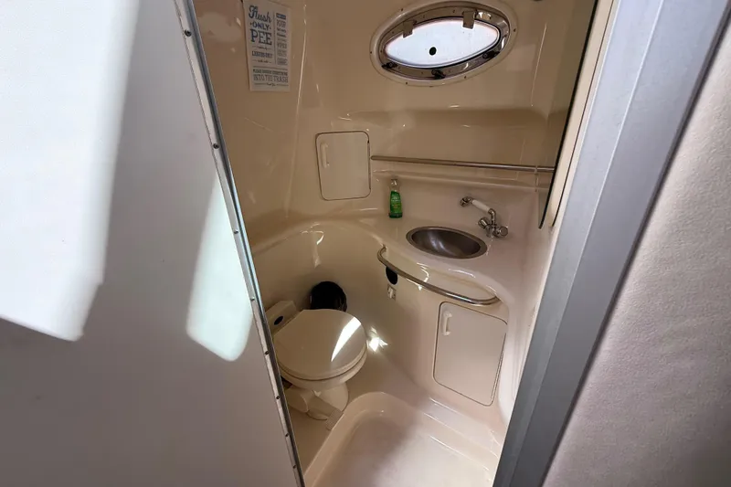 Slide: The Image of Compact bathroom in 1996 Sea Ray 330 Sundancer boat with toilet, sink, and porthole. - 32