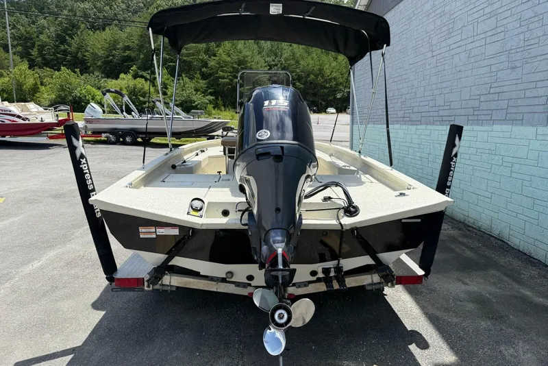 Slide: The Image of 2022 Xpress H20 BAY boat with outboard motor and canopy, parked outdoors. - 10