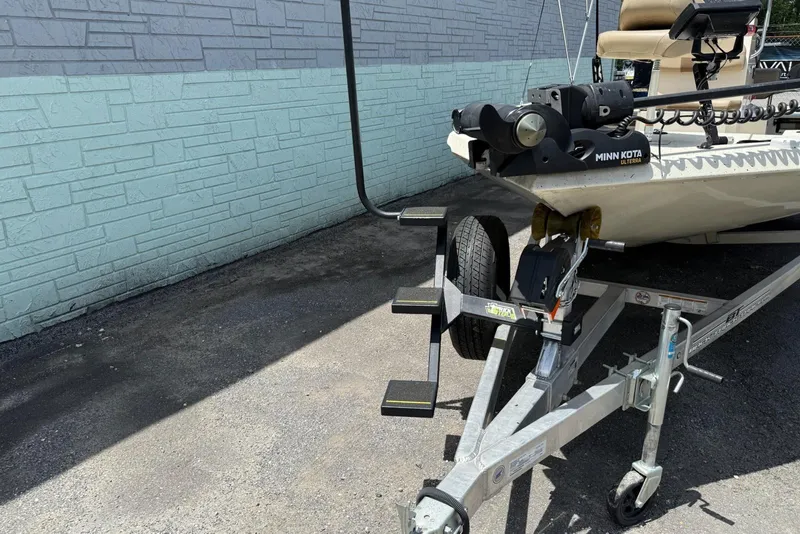 Slide: The Image of 2022 Xpress H20 BAY boat on trailer with Minn Kota motor, parked by a brick wall. - 3