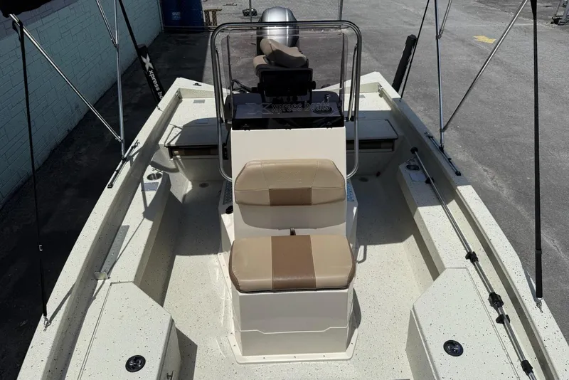 Slide: The Image of 2022 Xpress H20 BAY boat interior with seating and console, parked on pavement. - 8