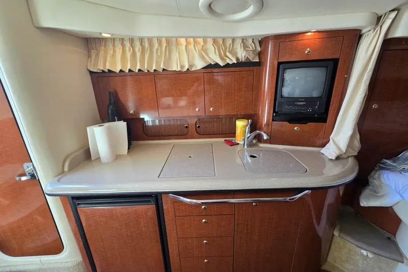 Slide: The Image of 2003 Sea Ray 340 Sundancer interior kitchen with wood cabinetry and compact appliances. - 21