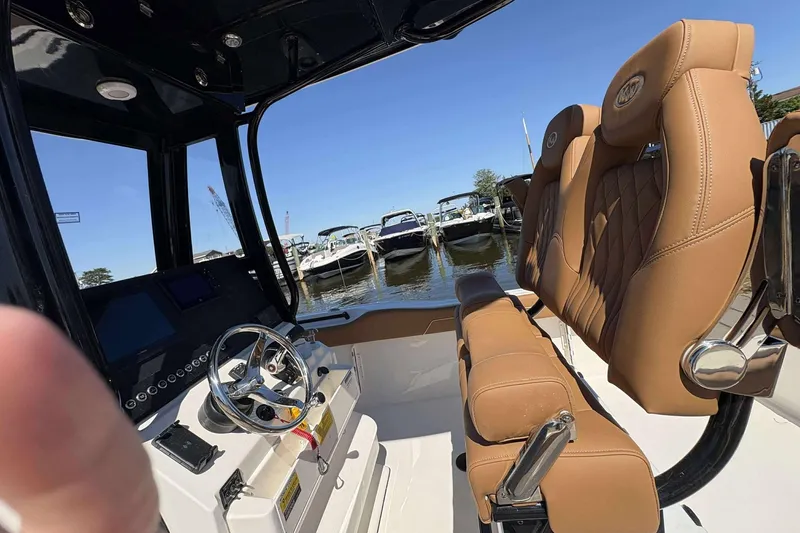 Slide: The Image of 2026 Key West 239 FS boat interior with tan seats and steering wheel, docked at marina. - 10