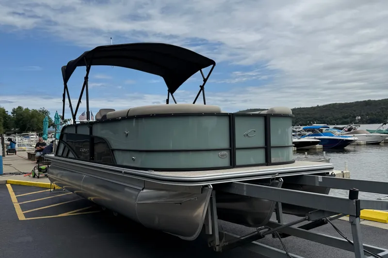 Slide: The Image of 2026 Crest 230 SLSC pontoon boat on trailer at marina, under cloudy sky. - 3