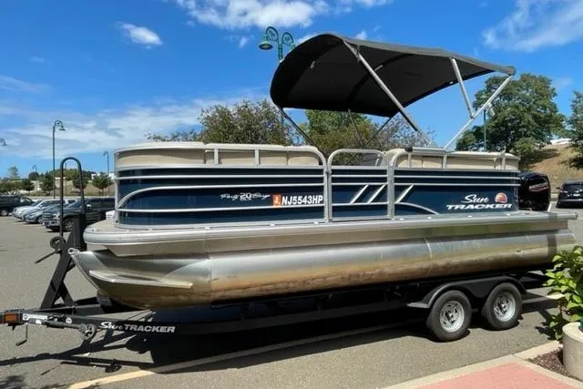 Slide: The Image of 2022 Sun Tracker Party Barge 20 DLX pontoon boat on trailer, parked outdoors. - 2
