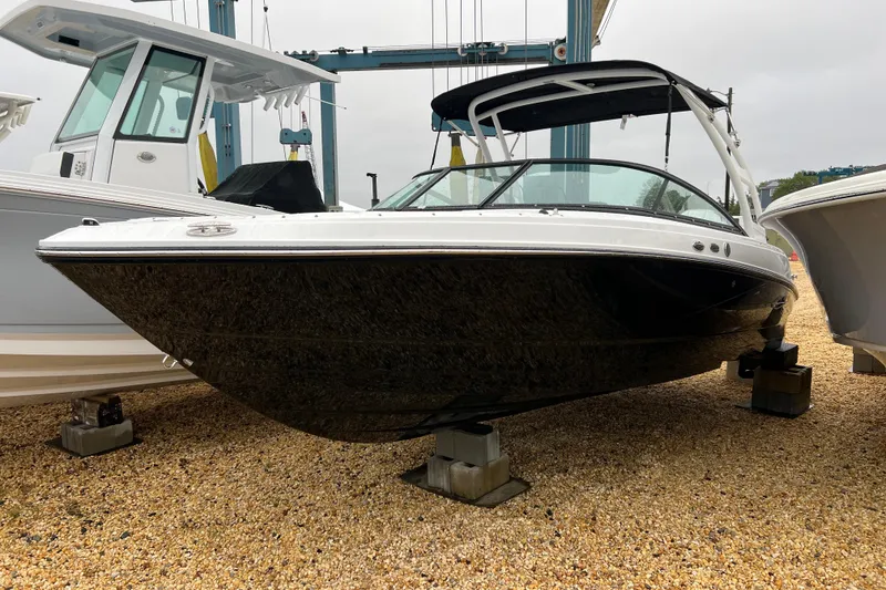 Slide: The Image of 2026 Monterey M-225 boat displayed on gravel, featuring sleek black and white design. - 0