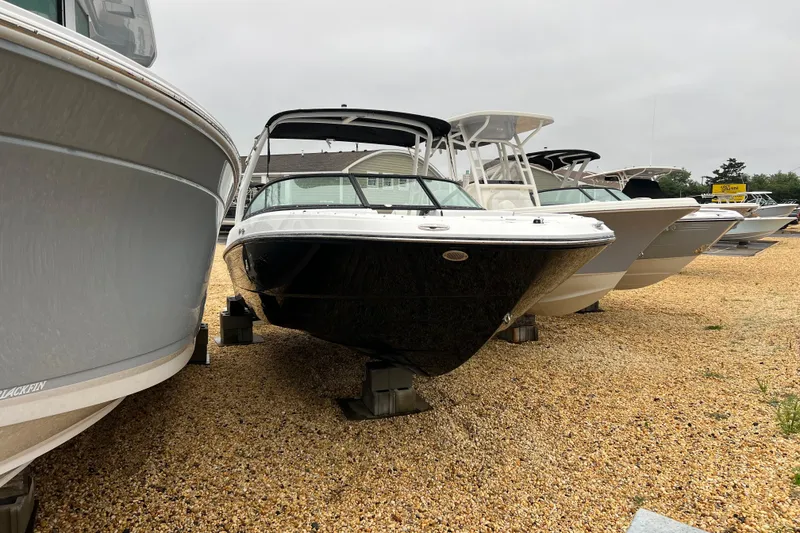 Slide: The Image of 2026 Monterey M-225 boat displayed on gravel lot among other boats. - 1