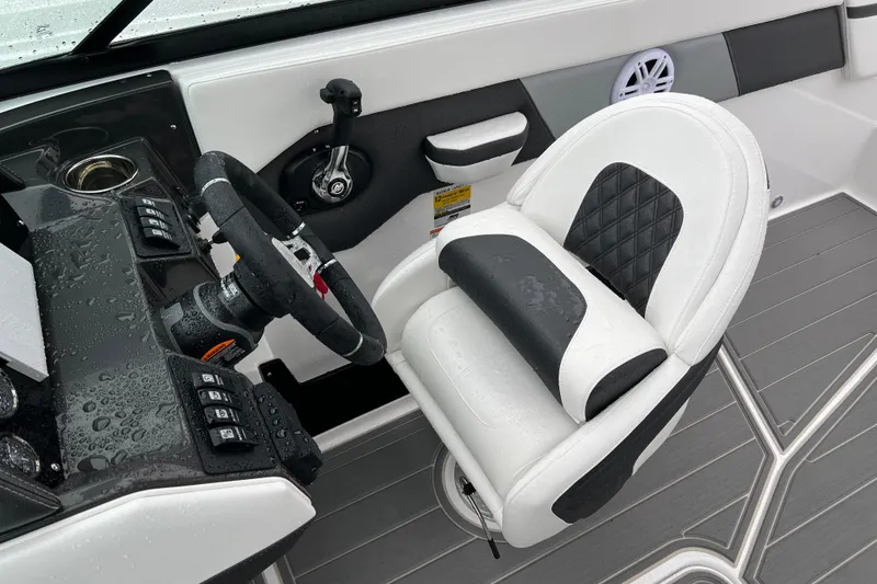 Slide: The Image of 2026 Monterey M-225 boat cockpit with steering wheel and cushioned seat, wet from rain. - 13