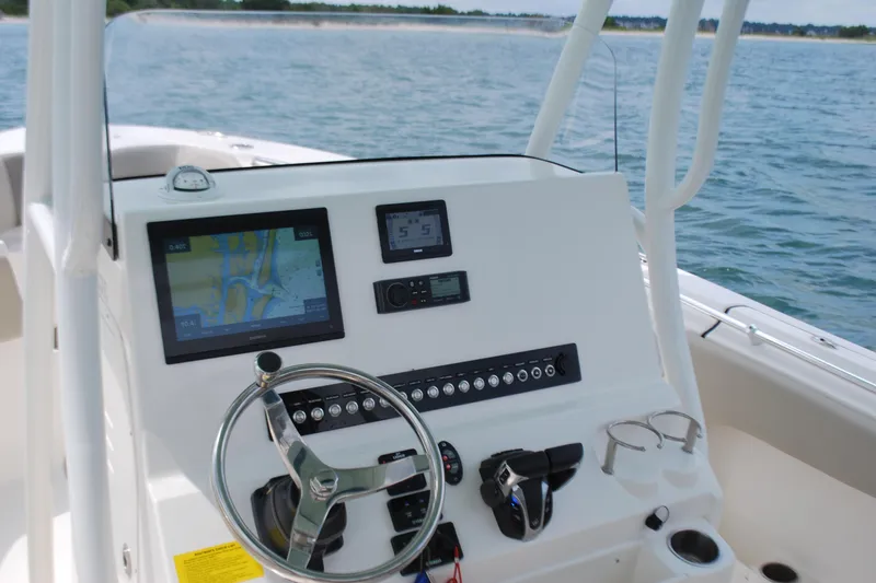 Slide: The Image of 2022 Key West 263 FS boat dashboard with navigation screens and steering wheel on open water. - 9