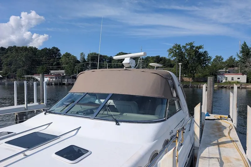 Slide: The Image of 1998 Sea Ray 370 Sundancer docked by a serene waterfront with clear skies. - 11