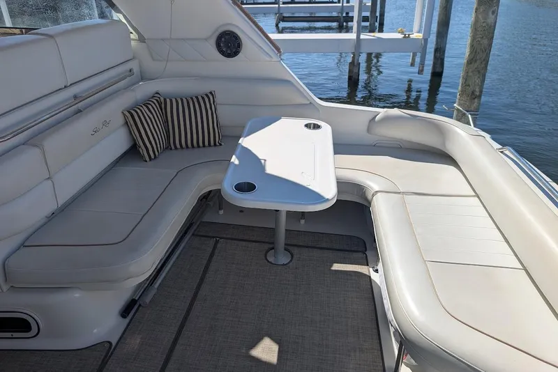 Slide: The Image of 1998 Sea Ray 370 Sundancer boat interior with cushioned seating and table by the water. - 16