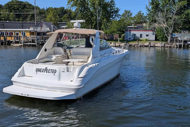 Slide: The Image of 1998 Sea Ray 370 Sundancer boat named "Unexpected" on calm water near docks. - 3