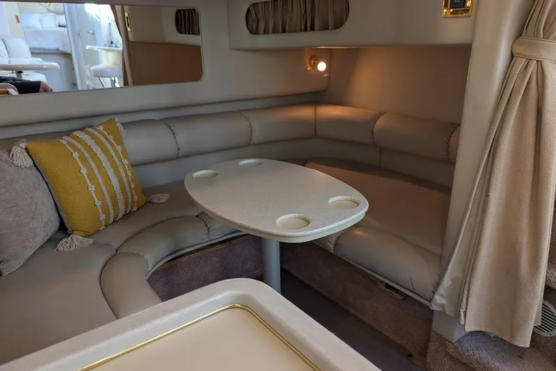 Slide: The Image of 1998 Sea Ray 370 Sundancer interior with cozy seating, table, and decorative pillows. - 36