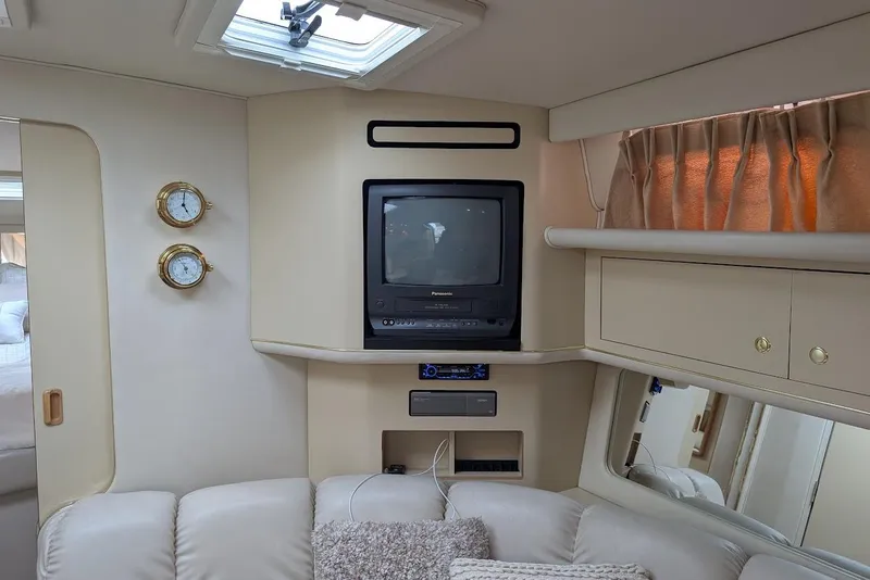 Slide: The Image of 1998 Sea Ray 370 Sundancer interior with vintage TV, cozy seating, and nautical decor. - 48