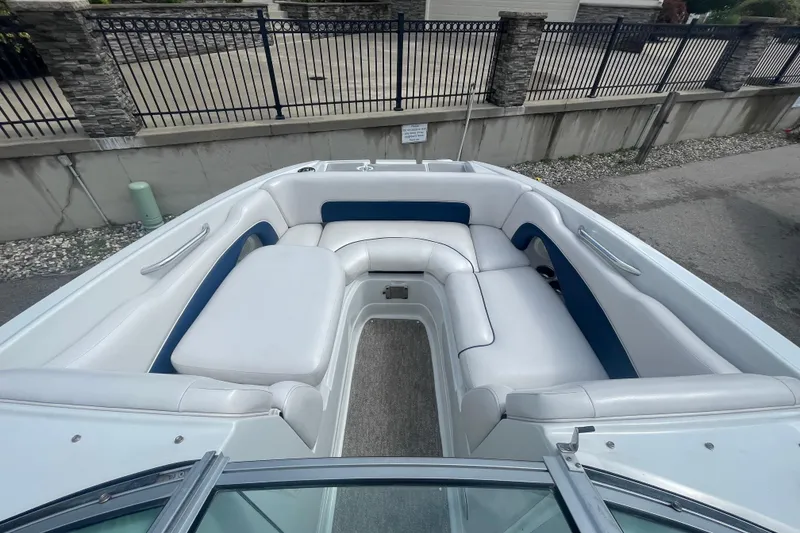 Slide: The Image of 2012 Crownline Eclipse 2 boat interior with white and blue seating, docked near a stone fence. - 19
