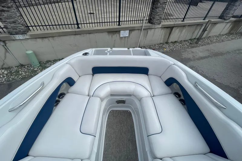 Slide: The Image of 2012 Crownline Eclipse 2 boat interior with white and blue seating, docked near a fence. - 20