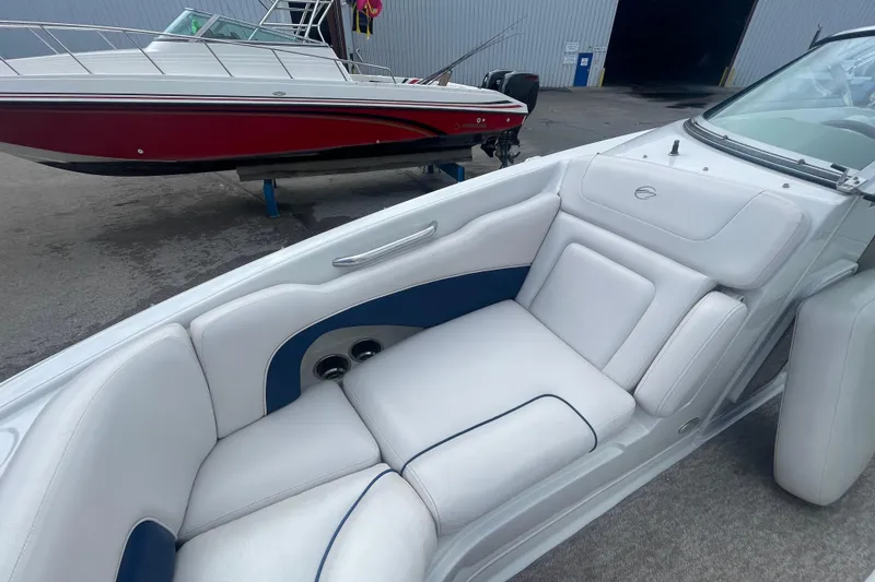 Slide: The Image of 2012 Crownline Eclipse 2 boat interior with white and blue seating, docked near a red boat. - 22