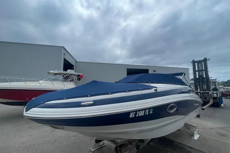 Slide: The Image of 2012 Crownline Eclipse E2 boat with blue cover, parked near a warehouse. - 24