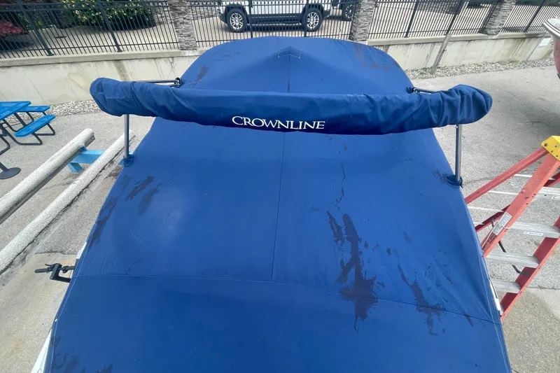 Slide: The Image of 2012 Crownline Eclipse E2 boat with blue cover, parked outdoors. - 26