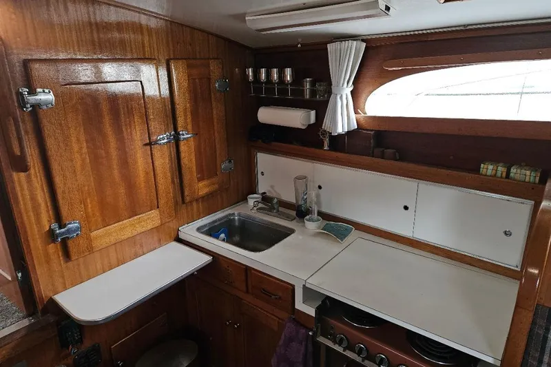 Slide: The Image of 1968 Egg Harbor Sedan kitchen with wooden cabinets, sink, and stove. Cozy nautical interior design. - 6