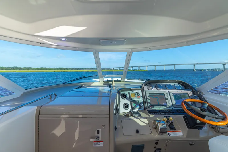 Slide: The Image of 2007 Sea Ray 40 Motor Yacht helm with navigation screens, steering wheel, and scenic water view. - 59