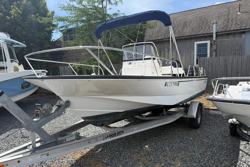 Slide: The Image of 2007 Boston Whaler 190 Montauk boat on trailer, parked outdoors near wooden building. - 0