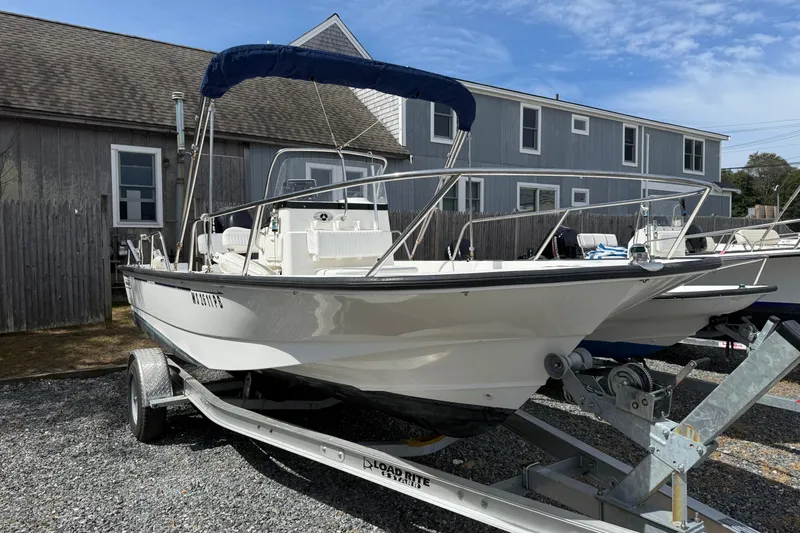 Slide: The Image of 2007 Boston Whaler 190 Montauk boat on trailer, parked near gray buildings. - 3