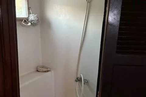 Slide: The Image of 1979 Sun Harbor Sundeck Trawler shower area with white walls and handheld showerhead. - 13