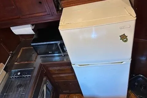 Slide: The Image of 1979 Sun Harbor Sundeck Trawler kitchen with fridge, microwave, and wooden cabinets. - 20