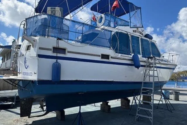 Slide: The Image of 1979 Custom Sun Harbor Sundeck Trawler on dry dock with blue accents and canopy. - 31