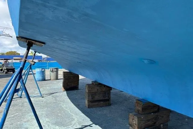 Slide: The Image of 1979 Custom Sun Harbor Sundeck Trawler on blocks, blue hull, dry docked for maintenance. - 33