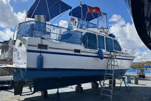 Slide: The Image of 1979 Custom Sun Harbor Sundeck Trawler on dry dock with blue accents and flags. - 35