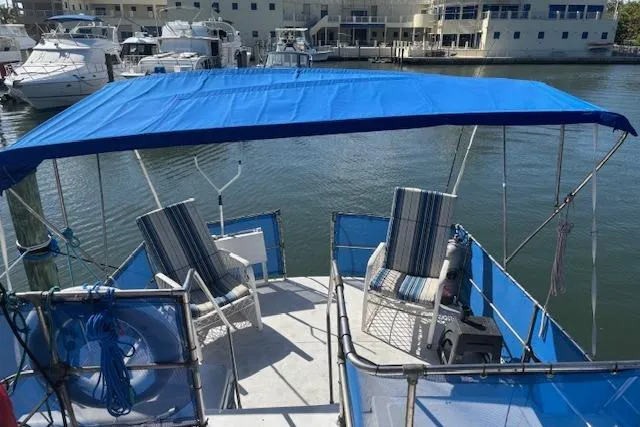 Slide: The Image of 1979 Custom Sun Harbor Sundeck Trawler with blue canopy and striped chairs at marina. - 4
