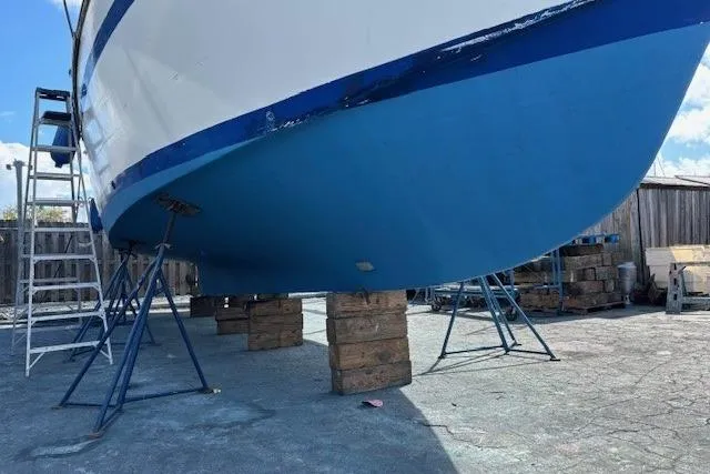 Slide: The Image of 1979 Custom Sun Harbor Sundeck Trawler on stands, blue hull, outdoor maintenance area. - 40