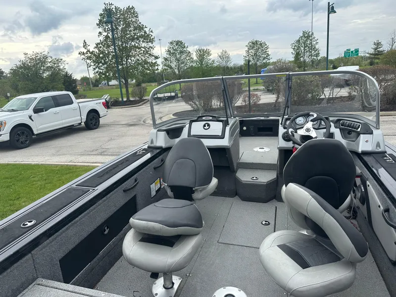 Slide: The Image of 2019 Tracker Targa V-18 WT boat interior with seating and dashboard, parked outdoors. - 2