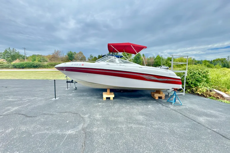 Slide: The Image of 1999 Four Winns 220 Horizon boat with red canopy on display outdoors. - 0