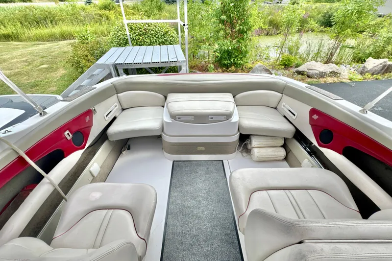 Slide: The Image of 1999 Four Winns 220 Horizon boat interior with white and red seating, surrounded by greenery. - 8