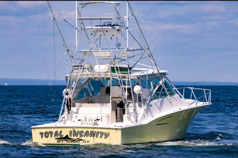 Slide: The Image of 2005 Cabo 40 Express boat named "Total Insanity" on open water. - 4