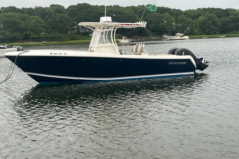 The Image of 2013 Sailfish 270 CC boat on calm water with lush green shoreline. - 0