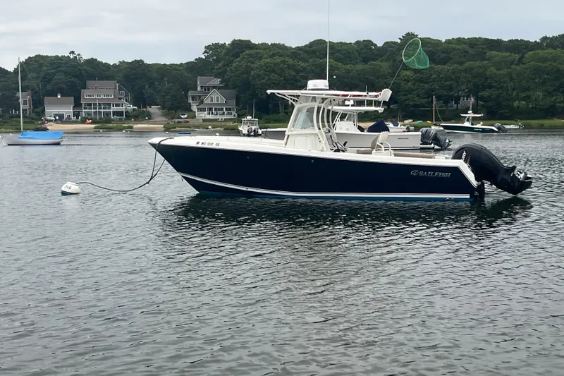 Slide: The Image of 2013 Sailfish 270 CC boat anchored in a calm bay with houses in the background. - 1