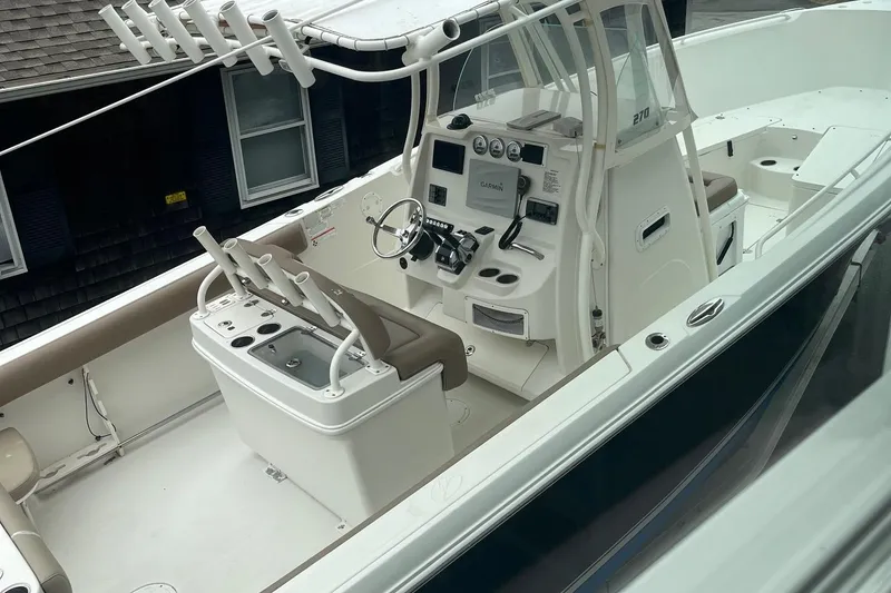 Slide: The Image of 2013 Sailfish 270 CC boat interior with helm, seating, and fishing rod holders. - 17